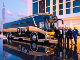 Luxurious modern Mercedes bus in Black and Gold design parked outside an event venue in Dubai, reflecting on the polished pavement, with happy passengers in formal attire arriving for a corporate event, and the Burj Khalifa visible in the distance.